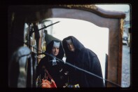 Two nuns looking at the camera. One of them wears glasses. The other has a camera around her neck.