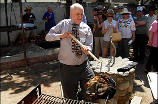 Charles Perry, L.A. Times food writer and President of the Culinary Historians of Southern California, lifts a hunk of beef from the pit in which it's been cooking for half a day.