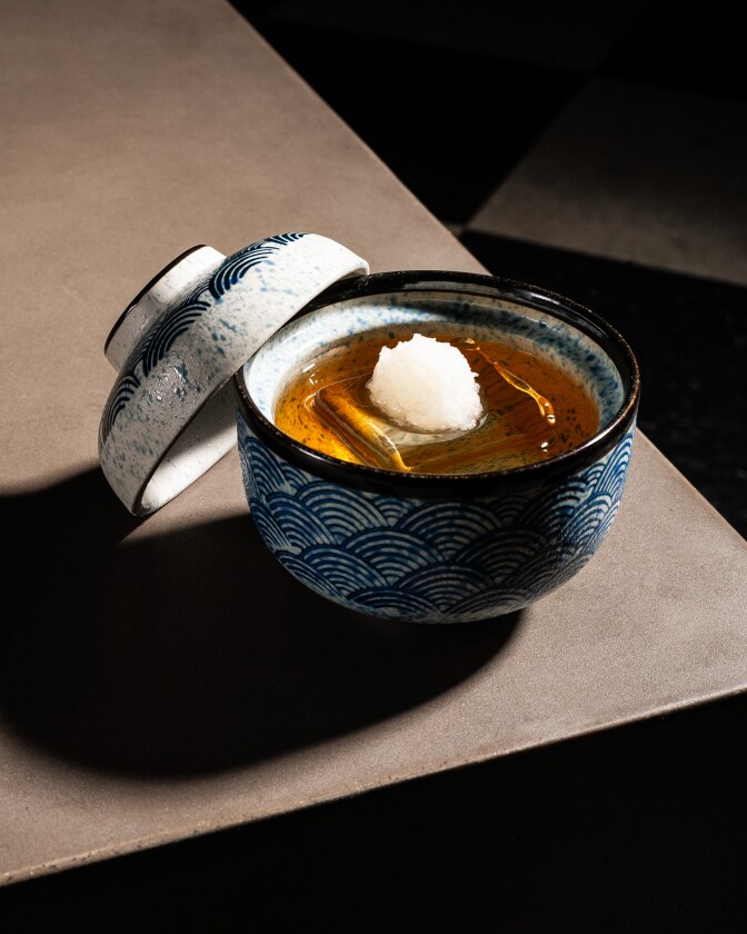 A chilled cocktail served in a blue-and-white patterned ceramic bowl with a mound of ice at its center.