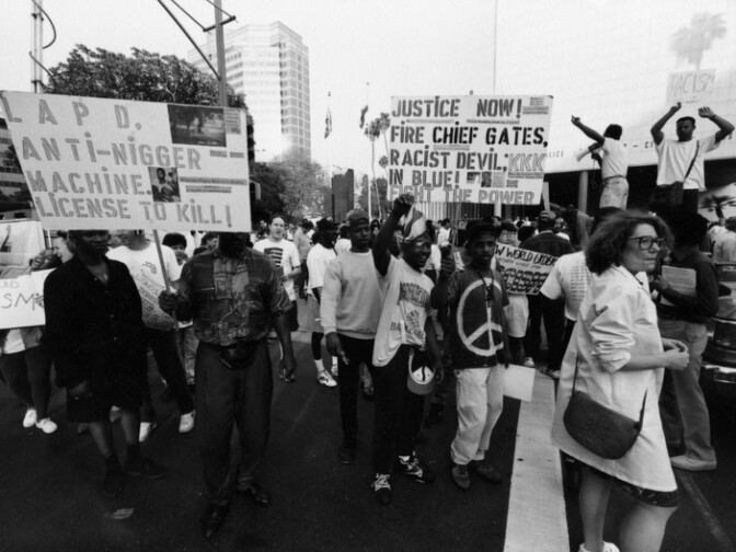 File: A group of people hold up signs advocating changes in the Los Angeles Police Department during the LA Riots unrest on April 29, 1992.