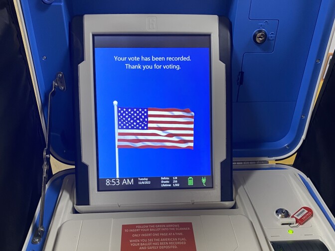 A screen inside a ballot booth that displays an American flag and reads "Your vote has been recorded. Thank you for voting."