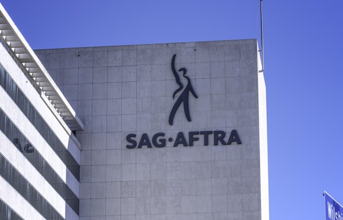 A multi-story stone facade building has SAG- AFTRA on its side with a figure gesturing to the sky
