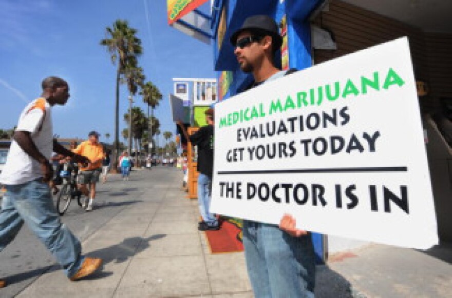 A man holds a placard advertising medical marijuana outside an evaluation clinic on Venice Beach in Los Angeles on October 9, 2009.