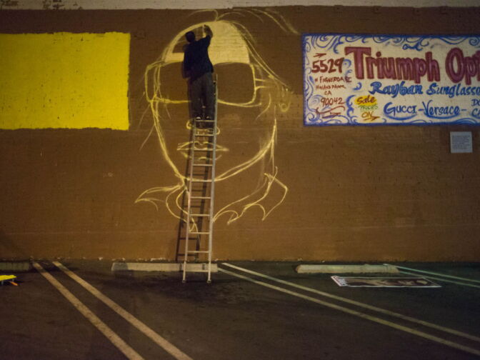 Graffiti Artist Edward Mompeller works on a mural on the side of the Triumph Optical shop in Highland Park.