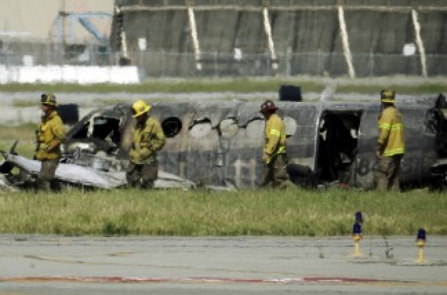 Firefighters view the wreckage of a twin-engine Beechcraft King Air airplane where it crashed and burned on takeoff from Long Beach, Calif., Airport on March 16, 2011.