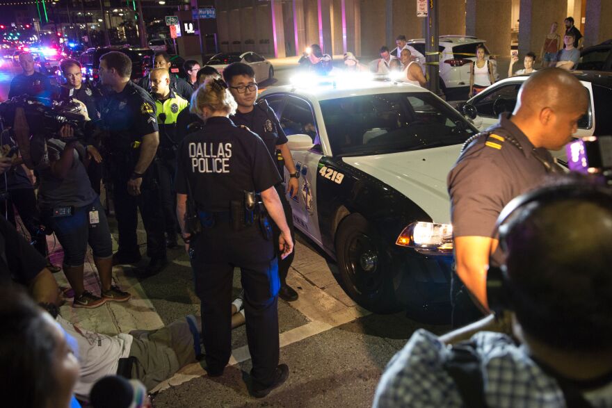 TOPSHOT - Police attempt to calm the crowd as someone is arrested following the sniper shooting in Dallas on July 7, 2016. 
A fourth police officer was killed and two suspected snipers were in custody after a protest late Thursday against police brutality in Dallas, authorities said. One suspect had turned himself in and another who was in a shootout with SWAT officers was also in custody, the Dallas Police Department tweeted.
 / AFP / Laura Buckman        (Photo credit should read LAURA BUCKMAN/AFP/Getty Images)