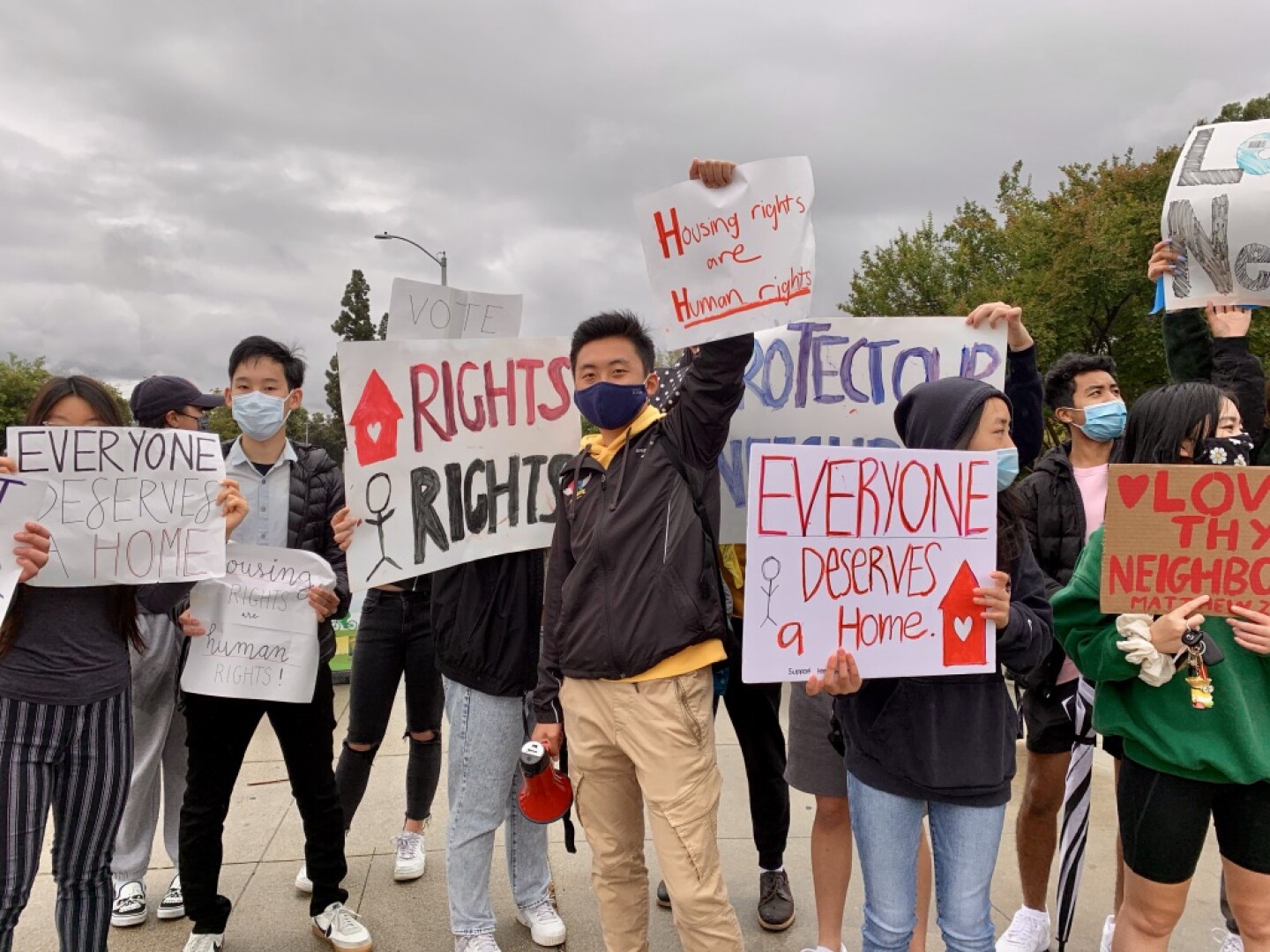 People who want to see housing for the homeless in Aracdia hold up signs that spell out their support.