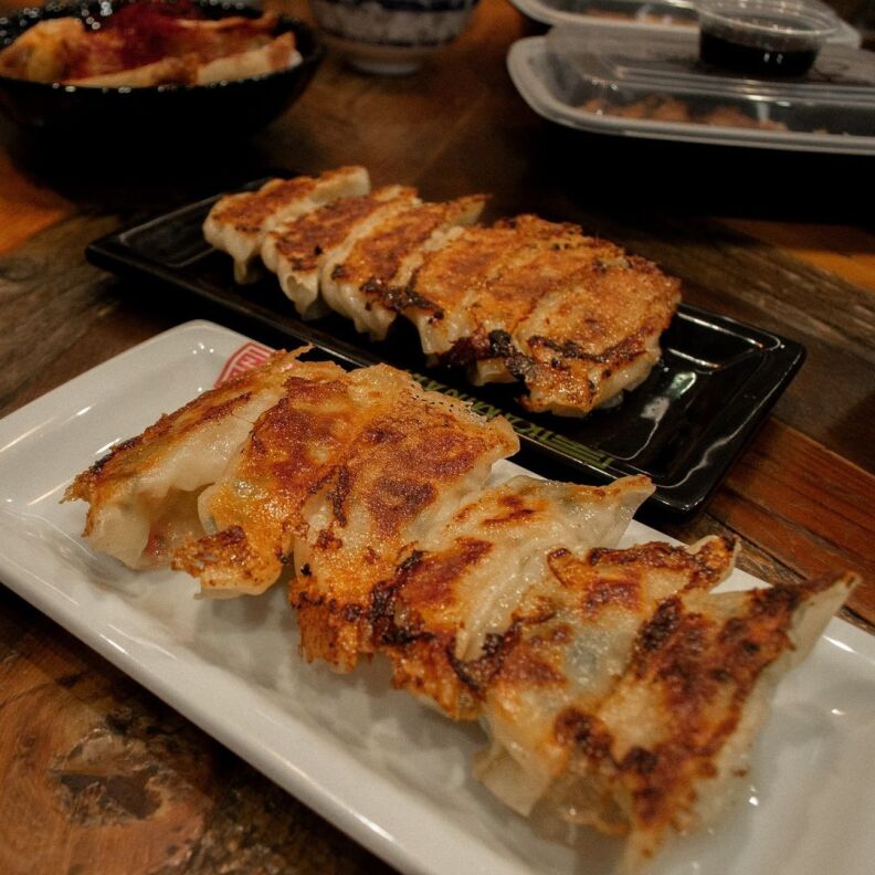 Crispy gyoza served on a black plate and a white plate.