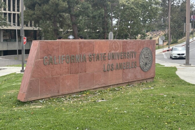 A stone sign at the entrance of Cal State University Los Angeles is set on grass. 