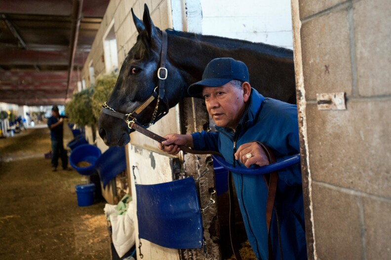 Assistant Trainer Ramon Gonzales stands in a stall with Top Knot, who is preparing for an afternoon race. Gonzales has worked at Cerin Racing Stables for 25 years.