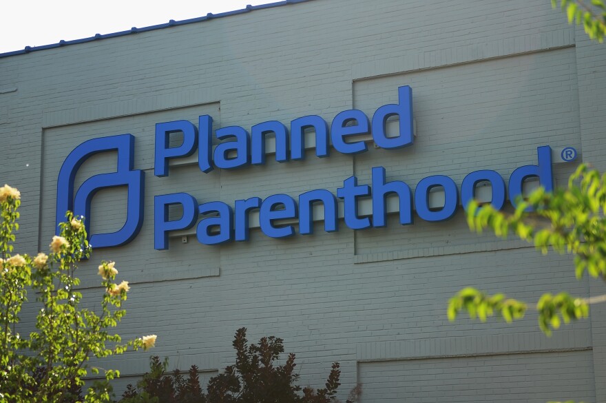 A light-colored brick building displays a large Planned Parenthood sign.