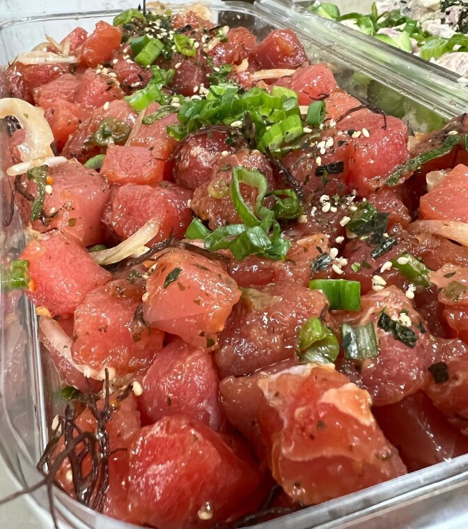 A try of Hawaiian-style ahi-tuna poke. The ahi tuna is red with cuts of garlic, onion and greens mixed in. 