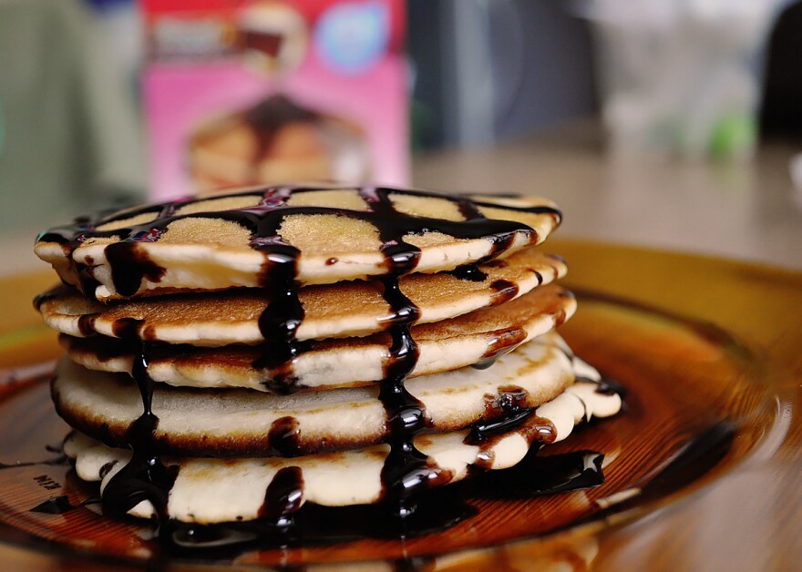 A stack of pancakes drizzled with chocolate syrup.