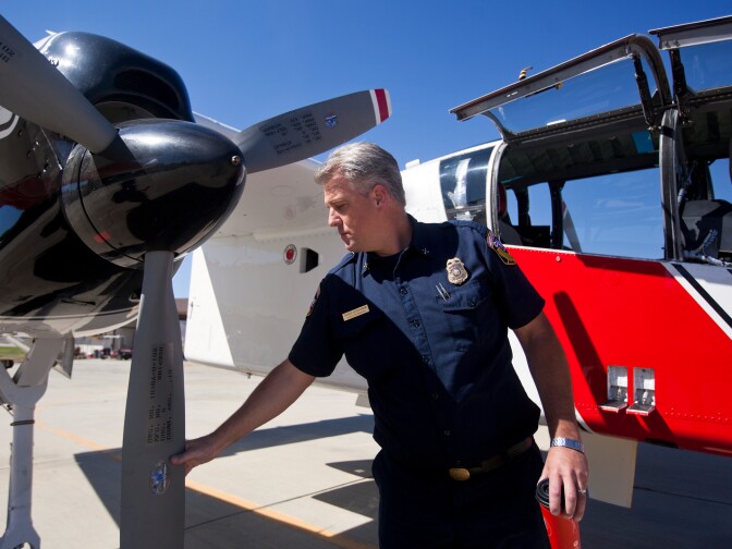 Battalion Chief Travis Alexander stands outside an air tactical aircraft. Alexander and other commanders can spend hours in the cockpit during a fire.