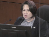 A Korean American woman of 50 with a bob sits at the city council dais.