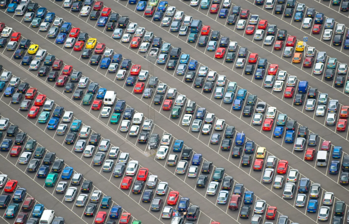 An aerial view of hundreds of cars parked in rows in a large parking lot