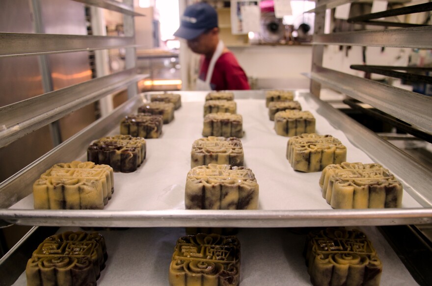 A baker walks past a tray of prepared Mooncakes at Olympic Bakery in Temple City, Calif., Monday September 24, 2012. The small pastries are made for the Chinese Moon Festival which takes place during the eight lunar month each year.