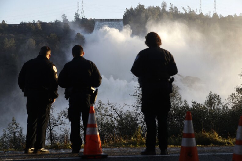 Police officers watch the Oroville Dam's main spillway from a lookout point on February 14, 2017, in Oroville, California.