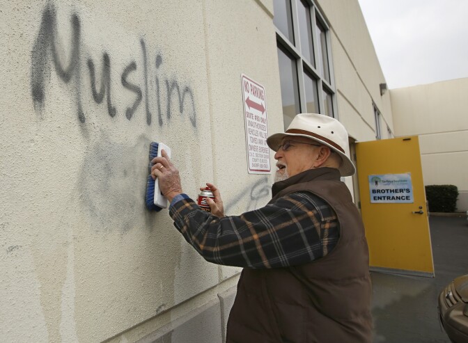 File: In this Feb. 1, 2017 file photo, Tom Garing cleans up racist graffiti painted on the side of a mosque in what officials are calling an apparent hate crime in Roseville, Calif. California's attorney general says the number of hate crimes increased about 11 percent last year, the second consecutive double-digit increase after years of decline. The report released Monday, July 3, 2017, shows 931 hate crimes statewide in 2016, nearly 100 more than in 2015.