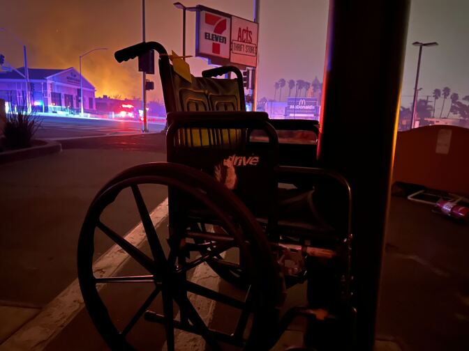 A wheelchair left in the 7-Eleven parking lot. Dark smoky clouds are seen in the background. 