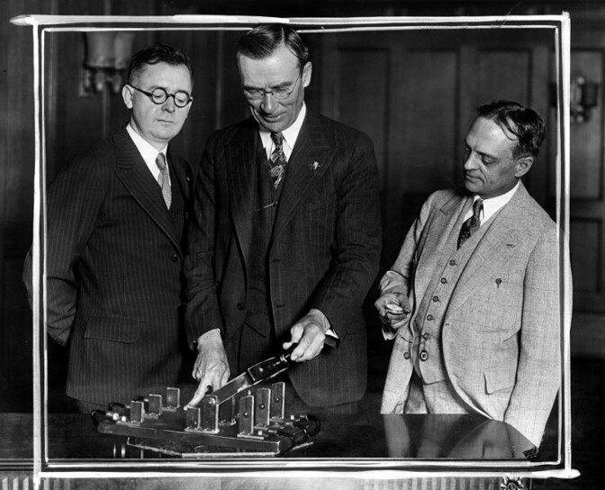 June 1, 1929: Mayor George Cryer about to push the electric switch which will light up green lanterns around LA, symbols of hospitable soda fountain services. L: A.H. Vossmeyer, representing druggists at whose stores the lanterns will be placed. R: A.V. Wainright, President of California Consumers Co., sponsors of the movement, which will revive the spirit of the old inns.