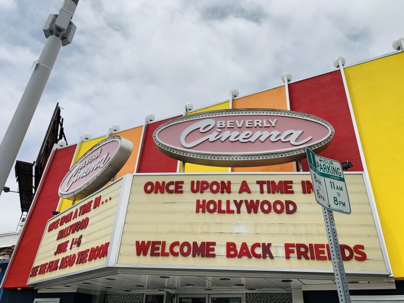 red, orange and yellow panels are behind an old theater marquee on a gray day