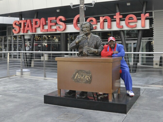 Darrell Bailey, known as Clipper Darrell, sits with the Chick Hearn statue in the Staples Center courtyard