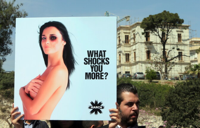 A man holds up a placard as he takes part in a rally to urge the Lebanese parliament to sign a law against domestic violence, on April 1, 2014, in Beirut. 