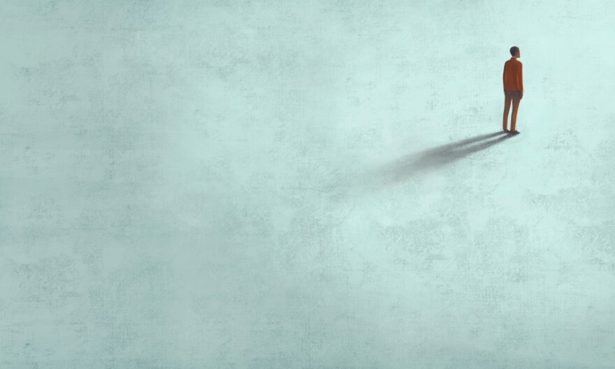 A dark figure appears to be standing, almost hip deep in a gray body of water, looking out on the horizon.