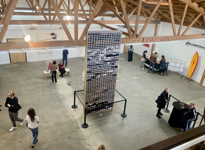 People surround a "tower" of images in a large art gallery space.
