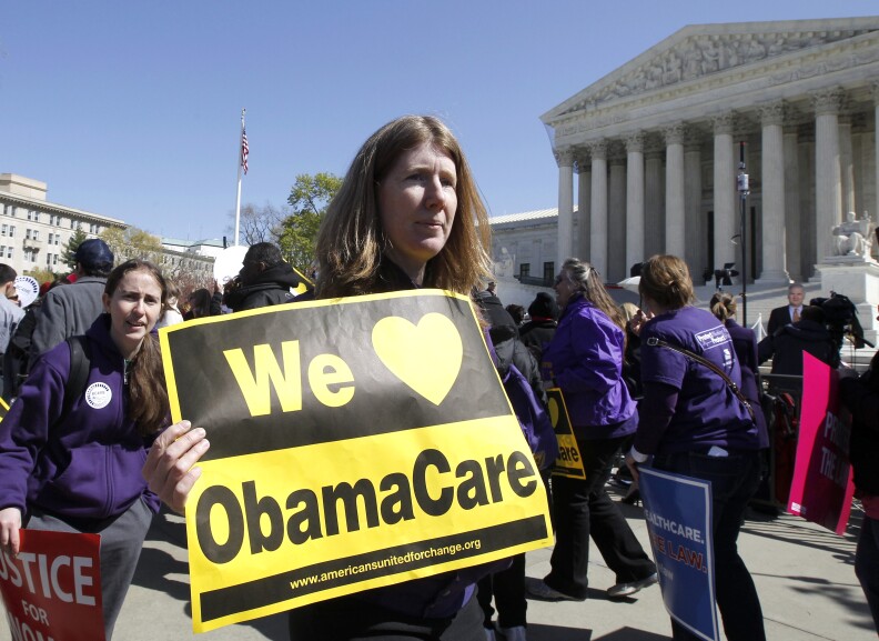 Holding a sign saying "We Love ObamaCare" supporters of health care reform rally in front of the Supreme Court in Washington, Tuesday, March 27, 2012.