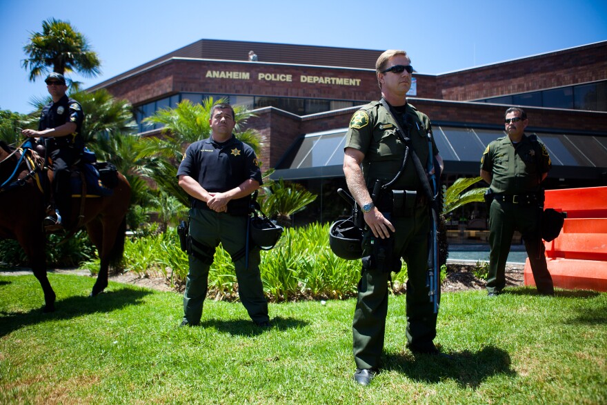 ANAHEIM, CA - JULY 29:  A line of police officers guard the Anaheim Police Department before a protest to show outrage for the several recent officer-involved shootings on July 29, 2012 in Anaheim, California. For the past week, protesters have clashed with police resulting in both property damage and many arrests.  (Photo by Jonathan Gibby/Getty Images)