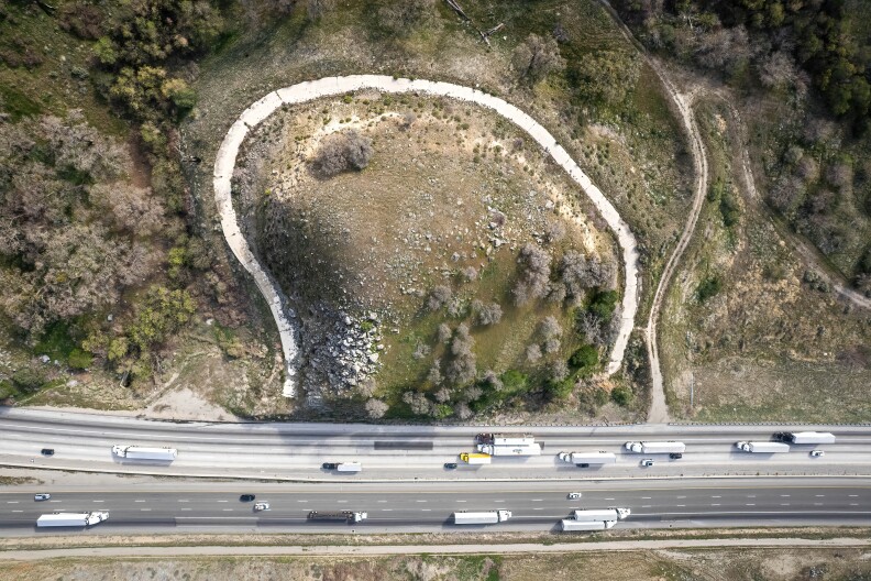 An ariel shot of a stretch of Interstate 5 that shows the old withered road on the hill behind it.