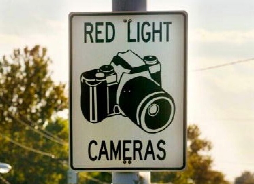 Cars drive past a red light camera sign in Laurel, Maryland.