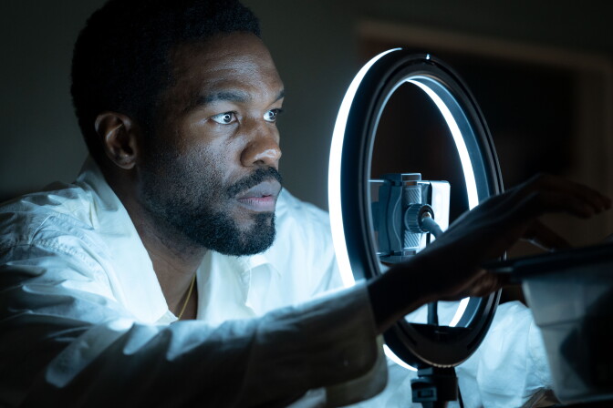 A photo from a TV show of a black man in front of a ring light.
