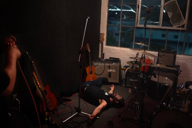 A man lies on the ground surrounded by musical instruments.