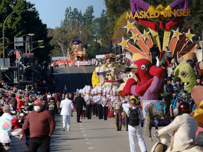 A parade of many people marches down a street.