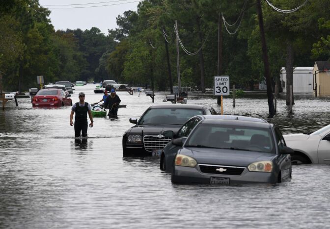 TOPSHOT - Local residents wade through flooded streets after Hurricane Harvey caused heavy flooding in Crosby, Texas on August 30, 2017.  
Monster storm Harvey made landfall again Wednesday in Louisiana, evoking painful memories of Hurricane Katrina's deadly strike 12 years ago, as time was running out in Texas to find survivors in the raging floodwaters. / AFP PHOTO / MARK RALSTON        (Photo credit should read MARK RALSTON/AFP/Getty Images)