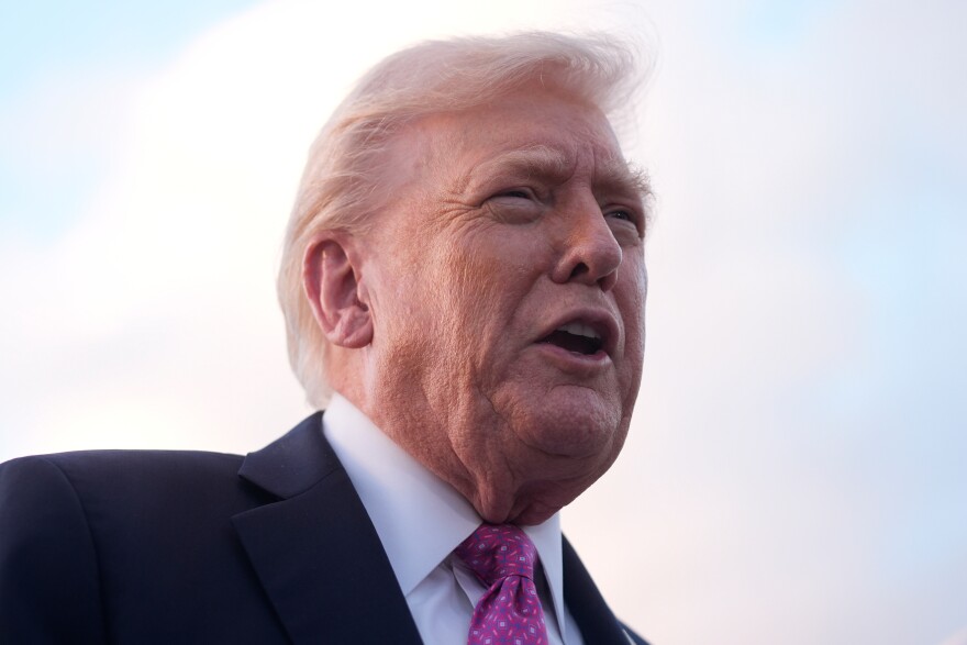 Donald Trump in a close up photo with a light blue sky behind him.