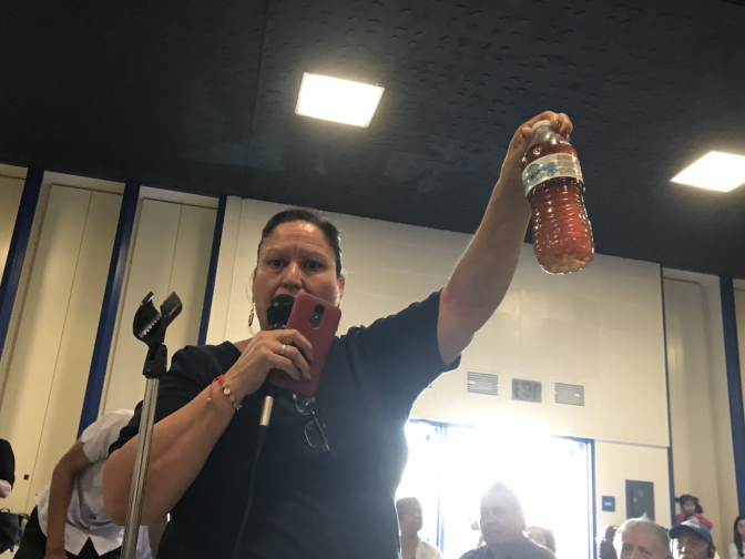 A Sativa water district customer holds up a bottle of the discolored water.