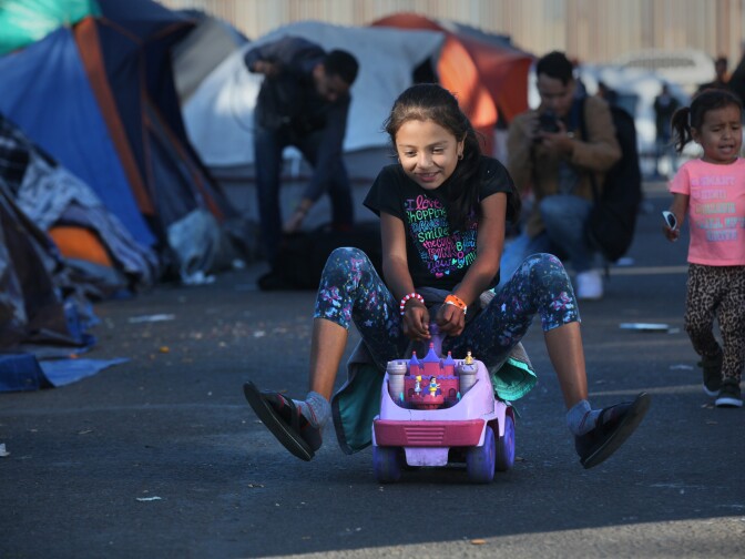 Tijuana, BAJA CALIFORNIA, Mexico - December 16, 2018. At the Benito Juarez Sports Complex near downtown Tijuana,  Asli Lopez, 9, rides a toy car through the middle of the migrant tents.

In Tijuana, Mexico, children members of the migrant caravan are learning to live in limbo as they move between shelters, settling in as much as possible to create a sense of normalcy, with help from NGOs, counselors and aid organizations. (Photo by Peggy Peattie)