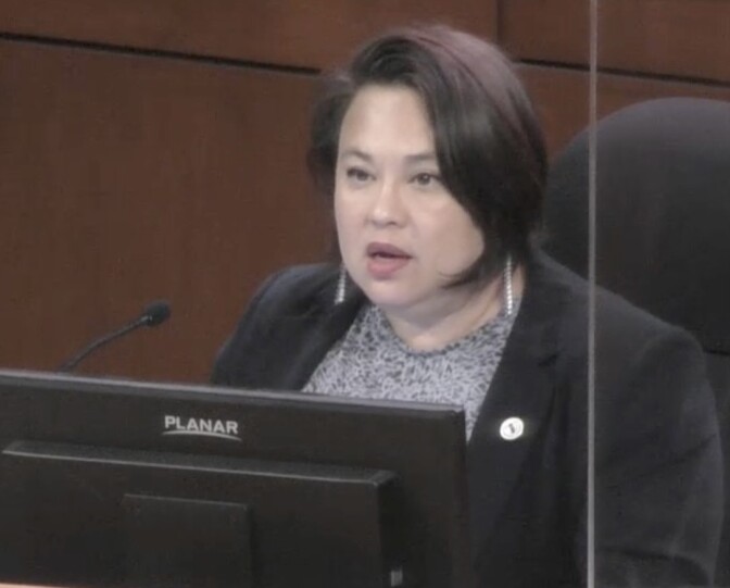 A Korean American woman with a bob haircut sits at the city council dais.