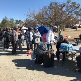 A line of homeless people at the Santa Ana riverbed wait to get connected with a motel room or shelter. on Tuesday, Feb. 20, 2018.