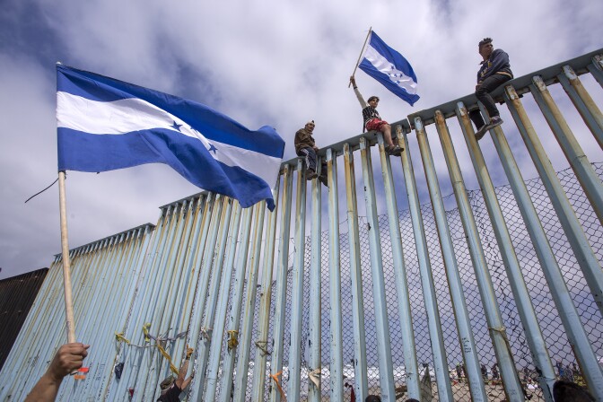 TIJUANA, MEXICO - APRIL 29: People hold Honduran flags at the border fence during a rally with members of a caravan of Central American asylum seekers and supporters on April 29, 2018 in Tijuana, Baja California Norte, Mexico. More than 300 immigrants, the remnants of a caravan of Central Americans that journeyed across Mexico to ask for asylum in the United States, have reached the border to apply for legal entry.   (Photo by David McNew/Getty Images)