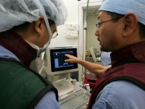 A new genetic test to gauge the aggressiveness of prostate cancer may help tens of thousands of men each year decide whether they need to treat their cancer right away or can safely monitor it.
The new test, which goes on sale Wednesday, joins another one that recently came on the market.
(Photo: Dr. Katsuto Shinohara (R) and Dr. Surat Dhonsombat look at a video monitor as they perform a bracytherapy operation on a man with prostate cancer at the UCSF Comprehensive Cancer Center in San Francisco)