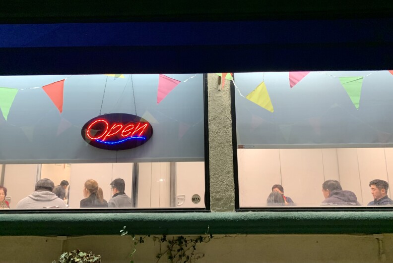 A nighttime exterior shot of diners eating inside of Taste of MP.