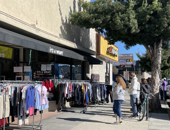 Shoppers peruse racks of clothes located on the sidewalk outside a resale store in Burbank, CA