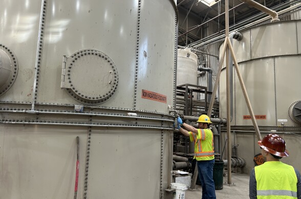 Large off-white circular tanks in a large warehouse. 