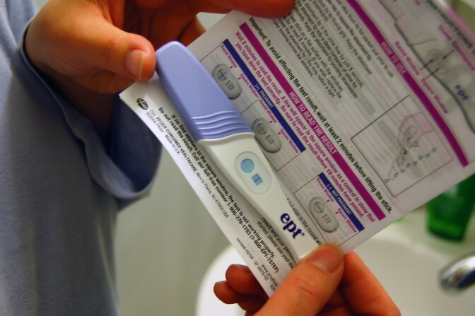 A woman inspecting a pregnancy test.