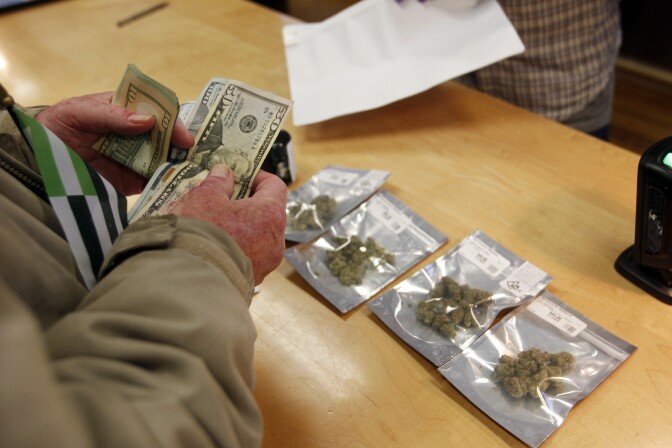 A customer purchases marijuana at Harborside marijuana dispensary, Monday, Jan. 1, 2018, in Oakland, Calif. Starting New Year's Day, recreational marijuana can be sold legally in California. (AP Photo/Mathew Sumner)
